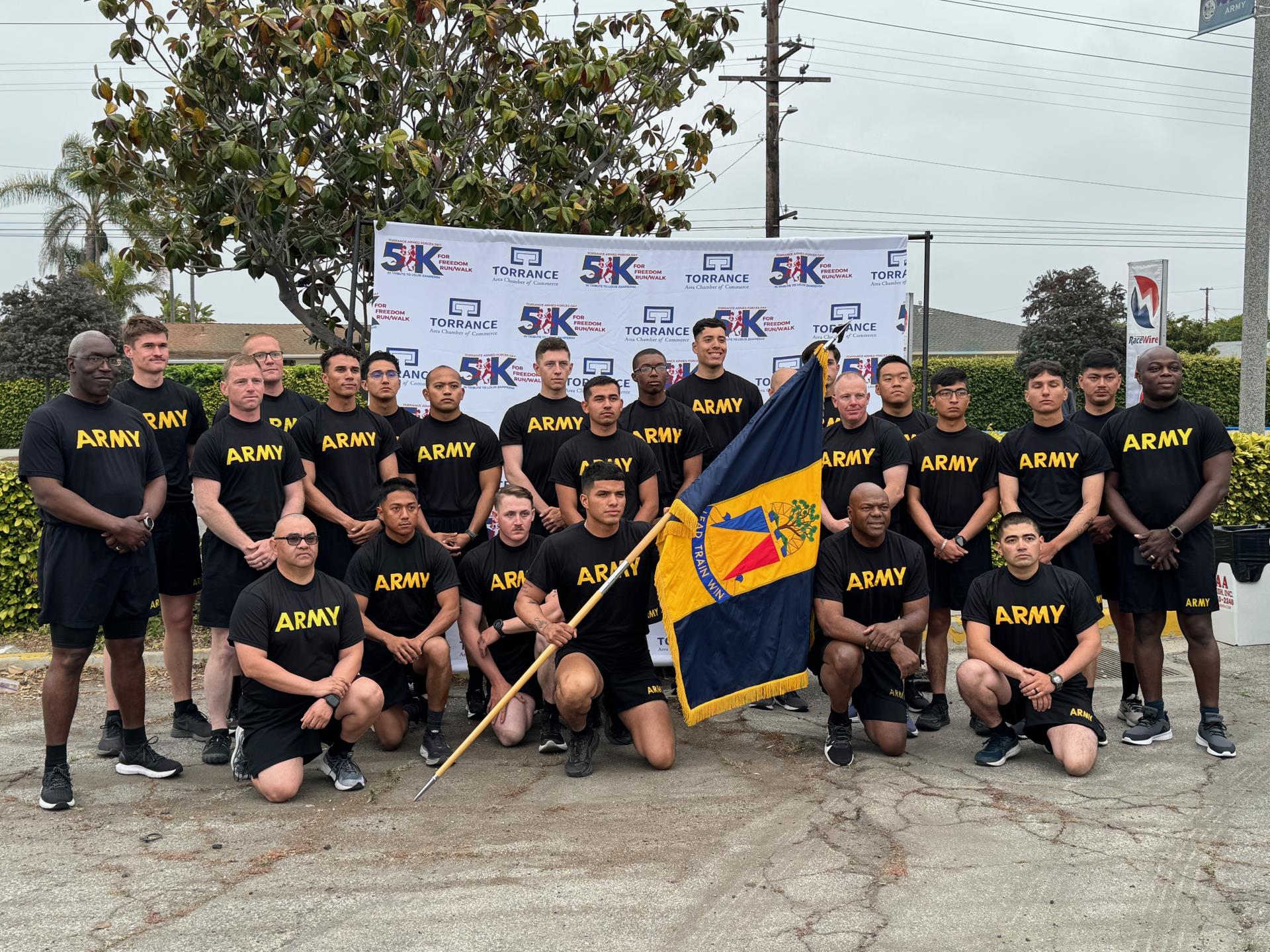 Group of men in army shirts with a flag posing in front of the 5K back drop