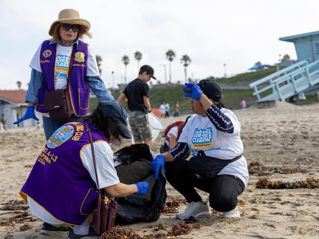 Three people picking up trash at the beach